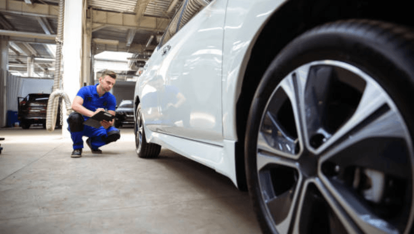 Collision repair technician inspecting vehicle damage and explaining repair timelines, parts availability, and repair processes to help drivers understand how long collision repair may take.