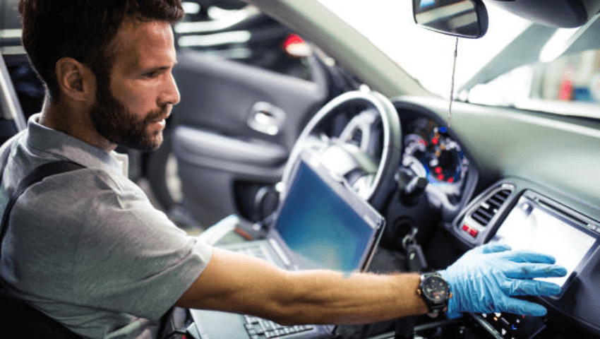Collision repair professional explaining repair costs to a customer while assessing vehicle damage, diagnostics, parts requirements, and safety system calibrations after an accident.